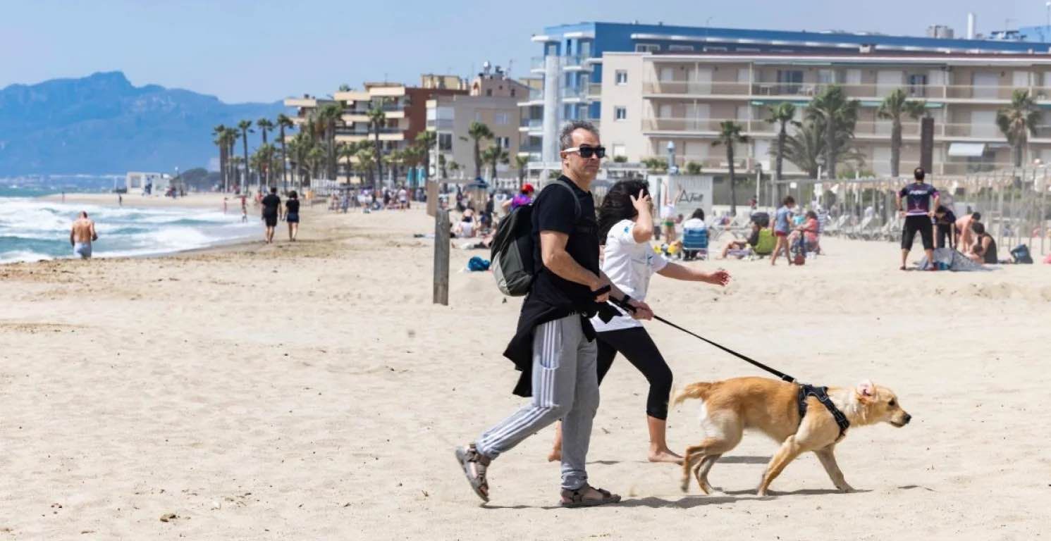 Pareja paseando a su perro en la playa de Ponent en Salou